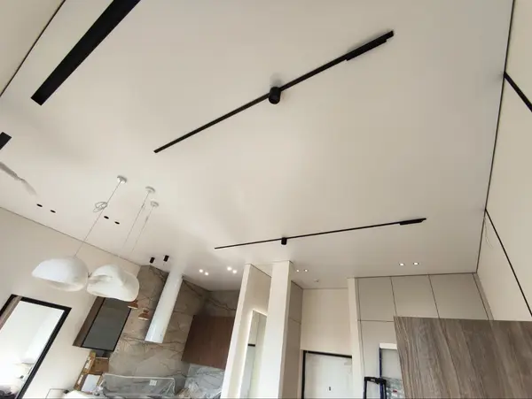 Тканевый натяжной потолок в гостиной — трековые светильники на белом матовом полотне